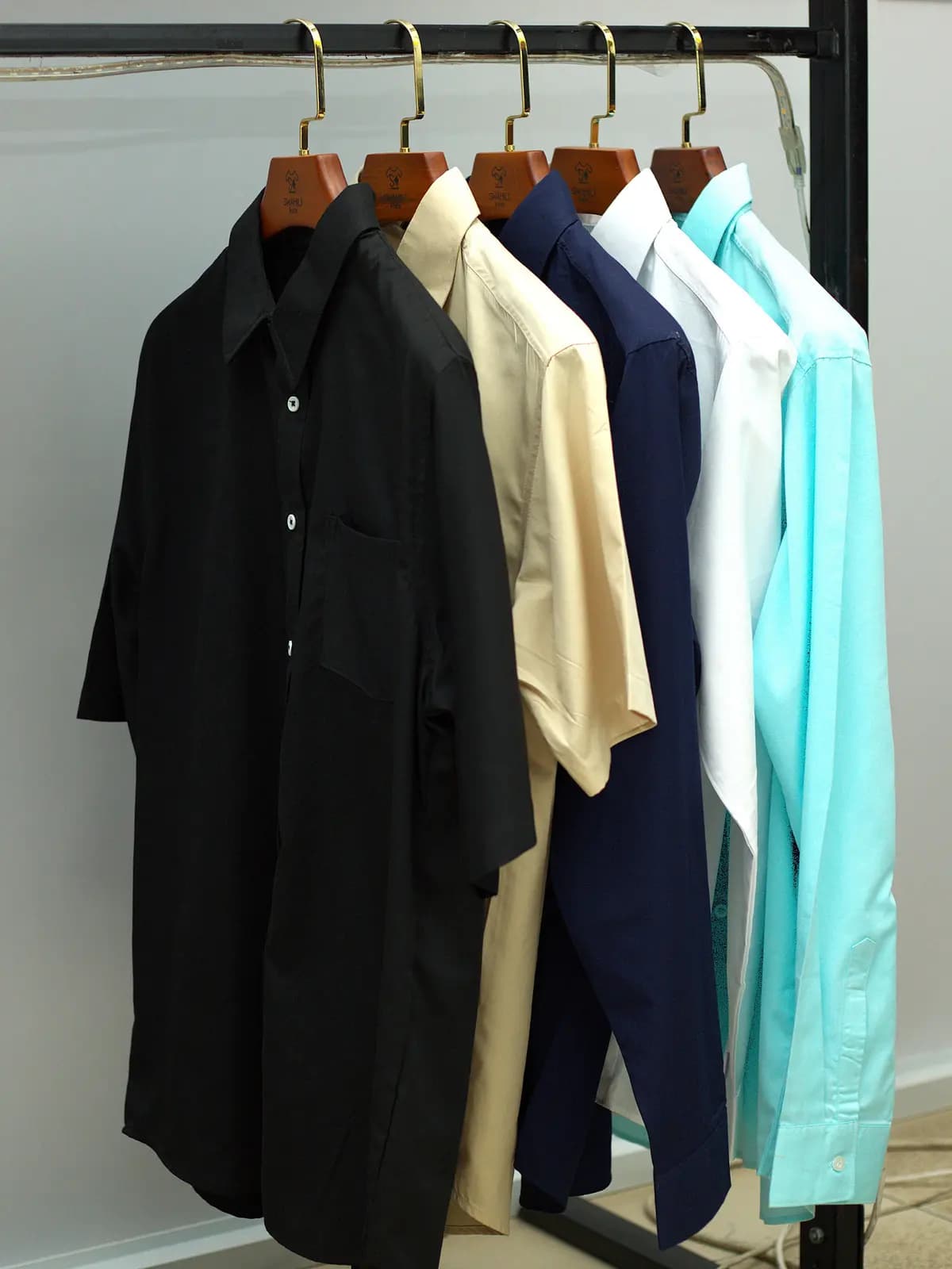 Woven shirts in black, cream and pale blue on the rail
