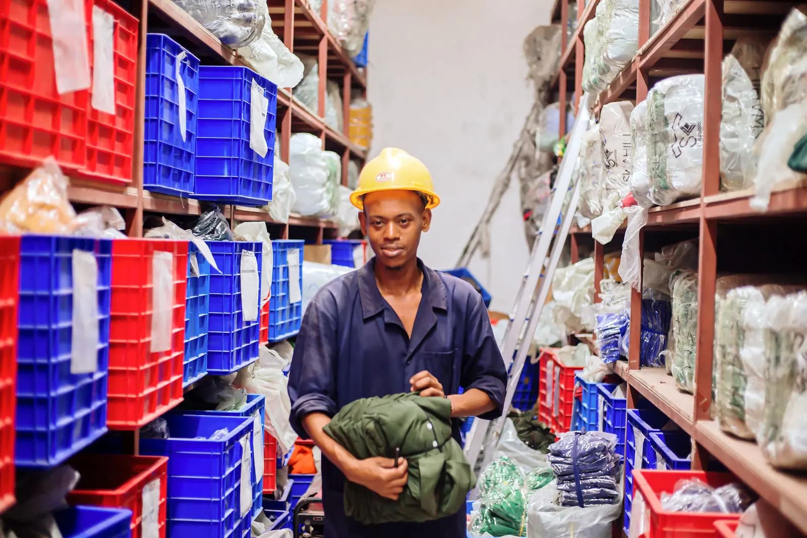 Worker in a hard hat among stock crates in the warehouse