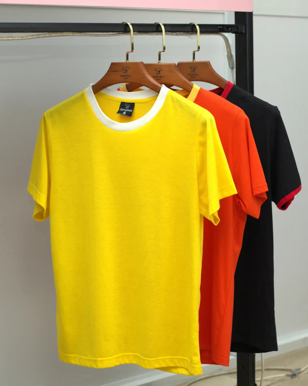 Bingwa t-shirts in yellow, orange and black on the rail at Swahili Knits